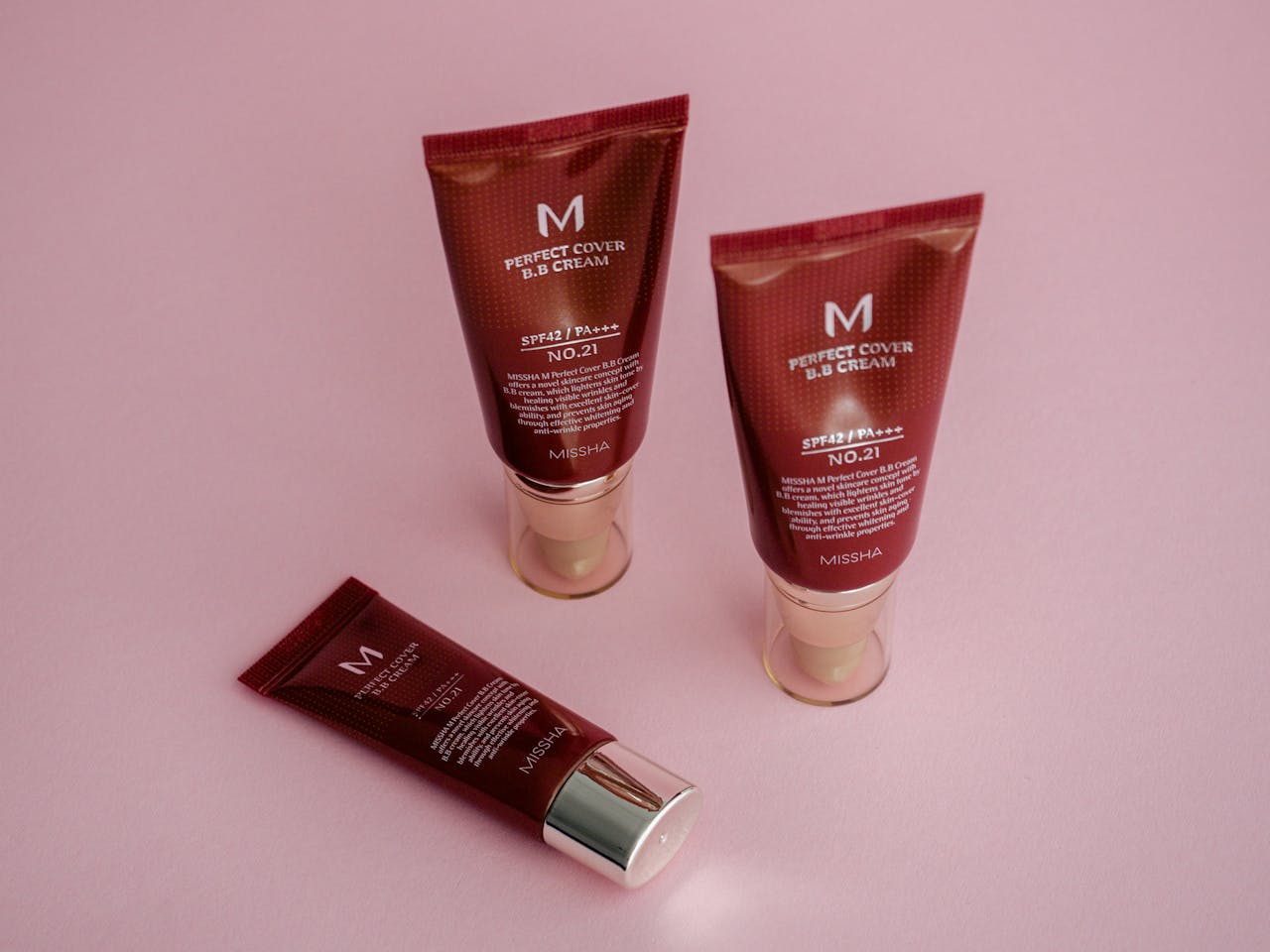 BB cream tubes on a vibrant pink background showcasing skincare and cosmetics.