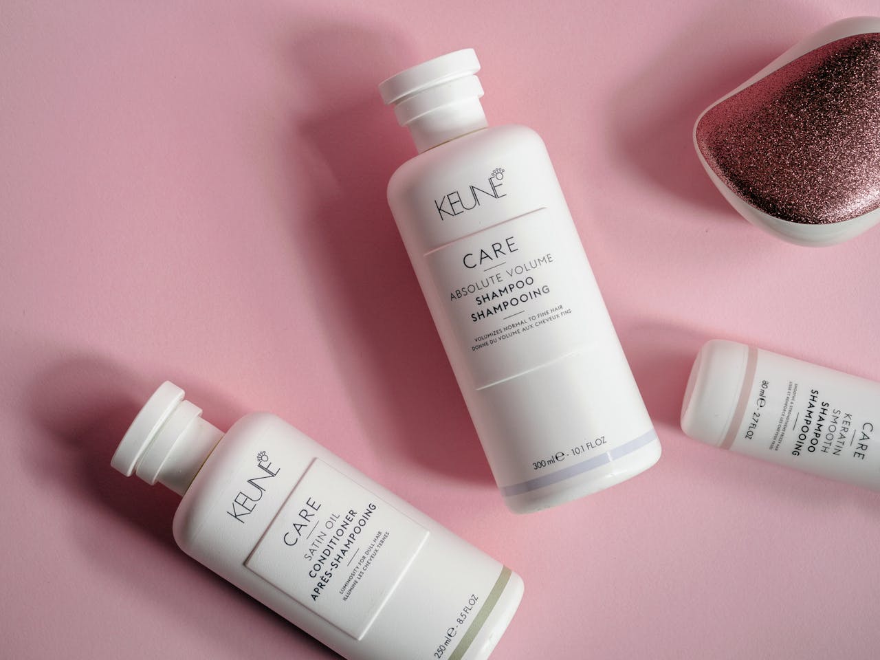 Elegant flat lay of shampoo and conditioner bottles on pink background, ideal for beauty brands.